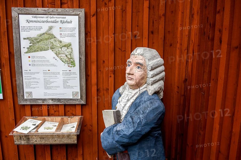 Wooden statue of botanist and founder of the binary nomenclature Carl von Linné with white hair and blue jacket in front of a wooden wall, Linnés Råshult, Älmhult, Kronobergs län, Småland, Sweden