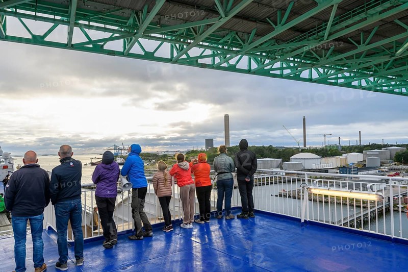 Group of people on a ship deck looking at the harbor crossing under the Älvsborgsbron suspension bridge under a cloudy sky on a ferry boat, Stena Line Gothenburg-Kiel, Gothenburg, Västra Götalands län, Sweden