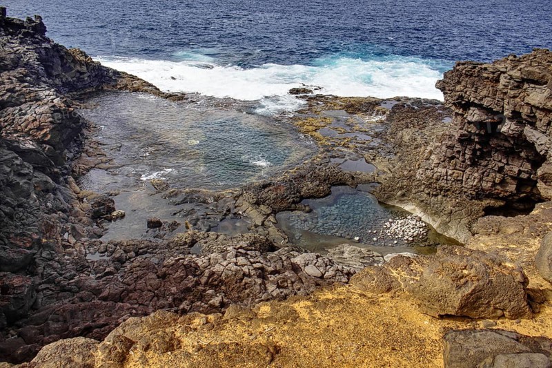 Rocky coastline with clear turquoise water pools and nearby waves, Yaiza Lanzarote