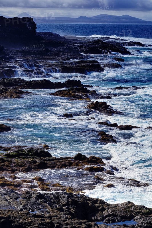 Rough sea with waves hitting cliffs under cloudy sky, Yaiza Lanzarote