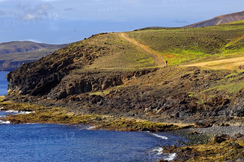 Cliff landscape with green path along the coast and views of the sea, Puerto Calero Lanzarote