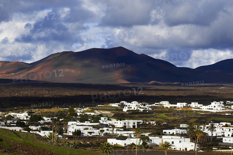 Partial view of the municipality of Yaiza at the foot of volcanic mountains under dramatic clouds in Lanzarote, Yaiza Lanzarote