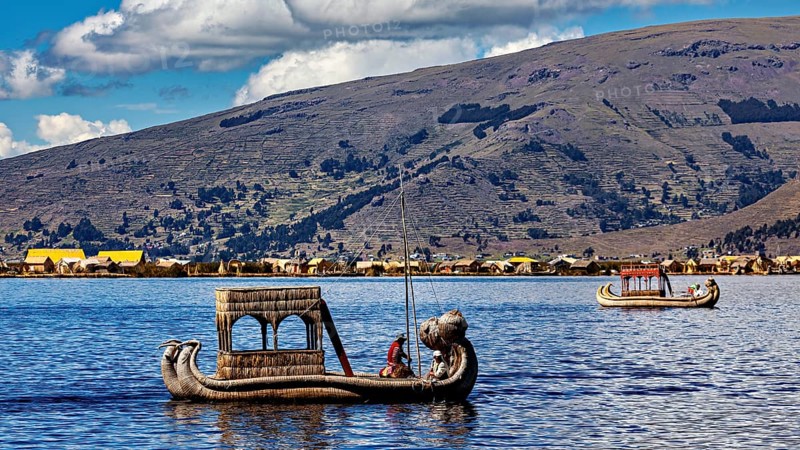 Two reed boats on a lake surrounded by mountains and a clear sky, The floating reed islands of the Uros in Lake Titicaca in Peru