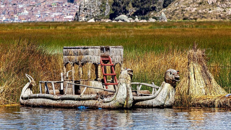 Traditional boat and reed structure in a protected area of the lake, The floating reed islands of the Uros in Lake Titicaca in Peru