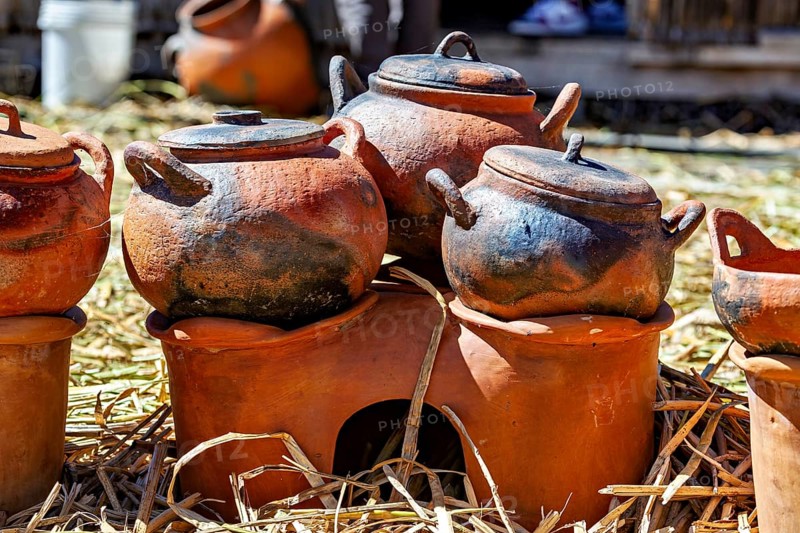 Clay pots and cooking areas arranged on a straw bed with rustic charm, The floating reed islands of the Uros in Lake Titicaca in Peru