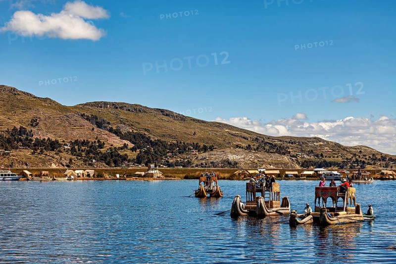 Traditional boats and people on a lake with a sweeping view of the shore, The floating reed islands of the Uros in Lake Titicaca in Peru