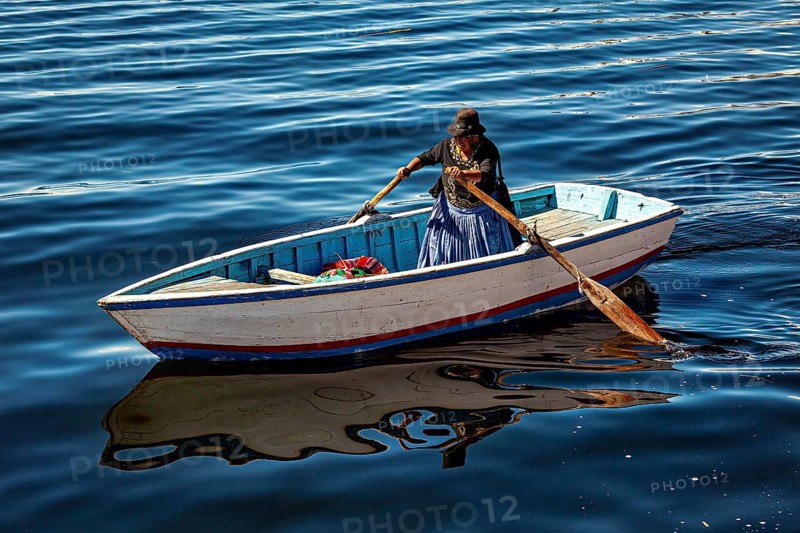 Woman rowing in a traditional boat on the calm waters of the lake, The floating reed islands of the Uros in Lake Titicaca in Peru