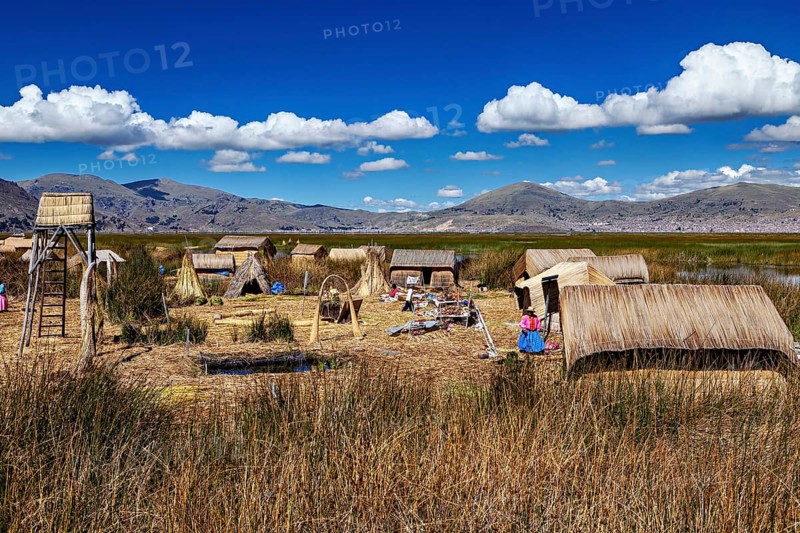 Reed village surrounded by mountains and under a clear blue sky, The floating reed islands of Uros in Lake Titicaca in Peru