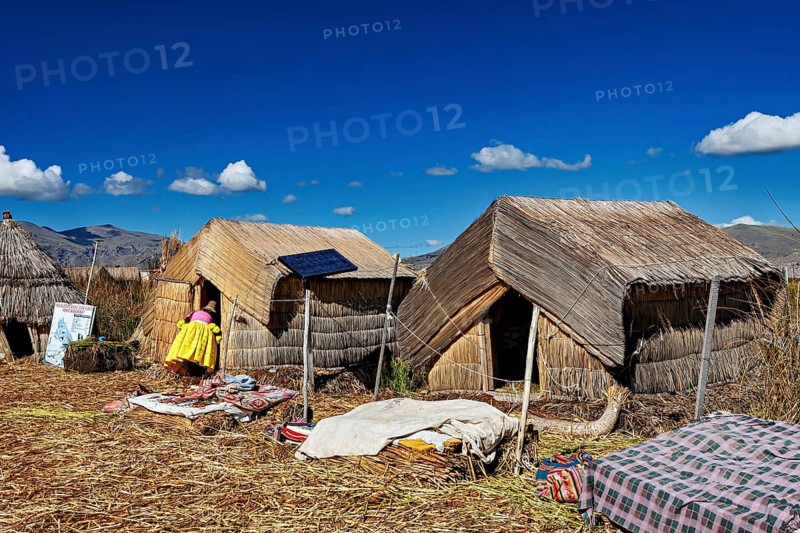 Reed huts with solar panels under a clear blue lakeside sky, The floating reed islands of the Uros in Lake Titicaca in Peru