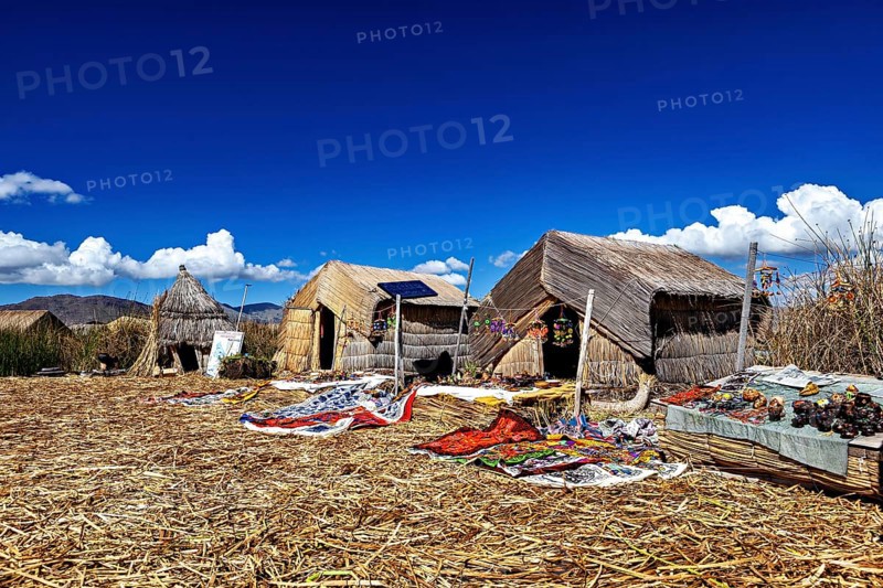 Straw huts on an island with traditional handmade objects in the foreground, The floating reed islands of the Uros in Lake Titicaca in Peru