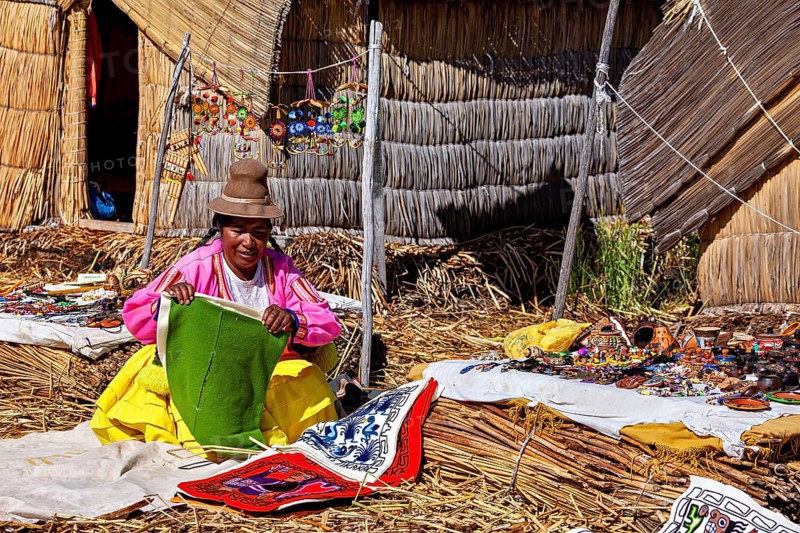 Woman in traditional clothing selling handmade goods in front of a hut, The floating reed islands of Uros in Lake Titicaca in Peru