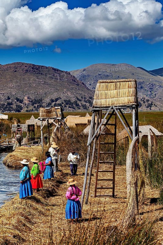 Women in traditional clothing at an elevated point overlooking the water, The floating reed islands of the Uros in Lake Titicaca in Peru