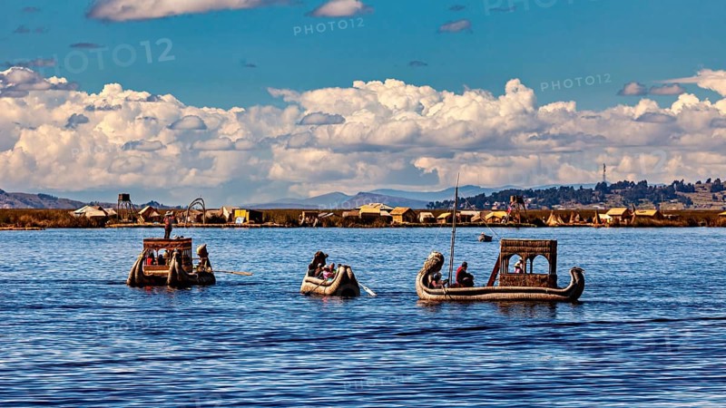 People ride in artfully designed reed boats on a wide lake, The floating reed islands of the Uros in Lake Titicaca in Peru