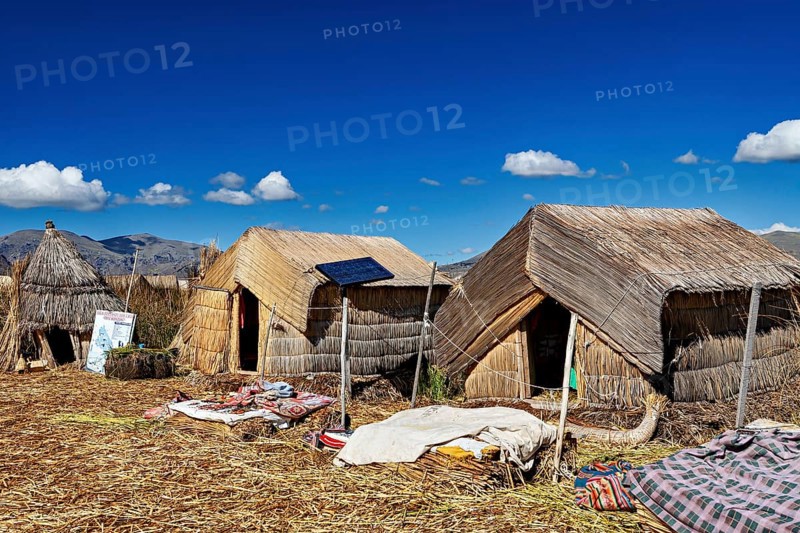 Traditional reed huts with solar panels on a lake surrounded by mountains, The floating reed islands of the Uros in Lake Titicaca in Peru