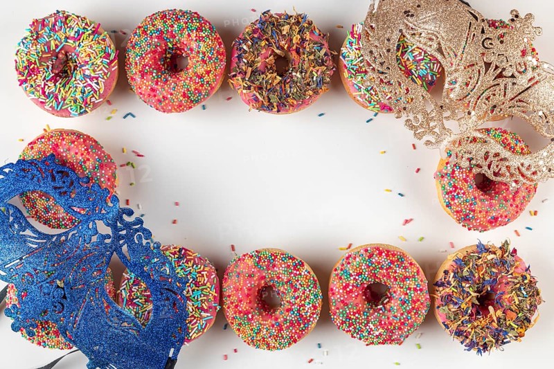 Shiny masks with colorful donuts and sprinkles frame a white area, carnival