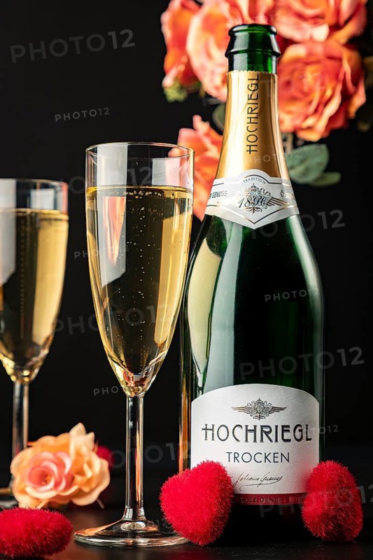 Hochriegl champagne bottle and filled glasses surrounded by roses and red hearts