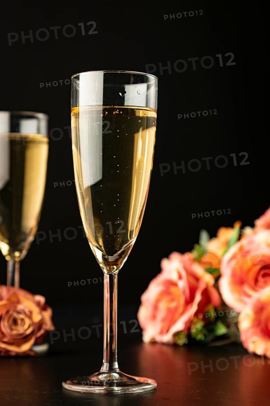Filled champagne glasses with roses, dark background