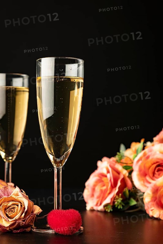 Filled champagne glasses with roses and heart, dark background, Valentine's Day
