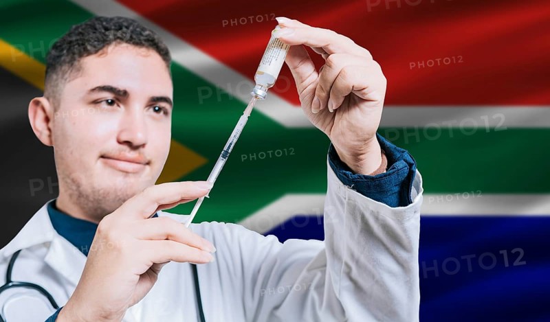 Doctor holding syringe on South Africa flag background. Medical professional holding syringe with South African flag in the background