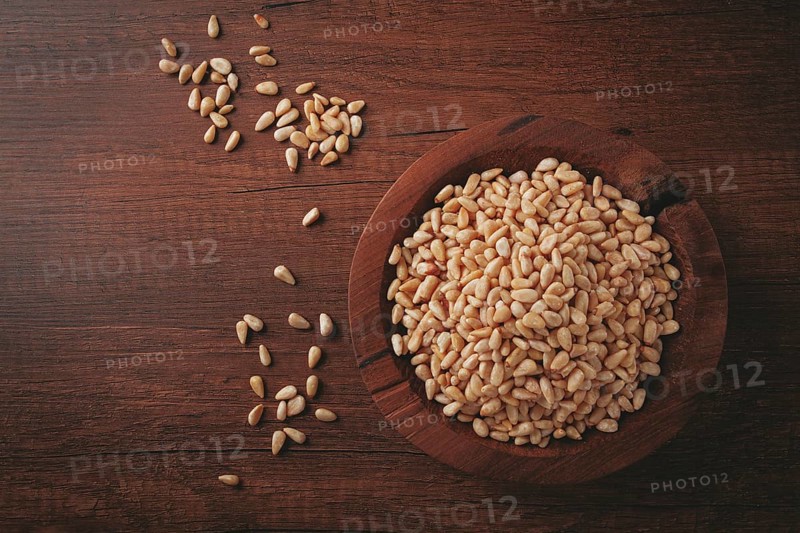 Peeled pine nuts, in a wooden bowl, on a wooden table, close-up, no people