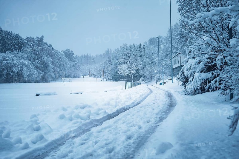 A snowy road leads through a wintry landscape with trees and houses, Besenfeld, Black Forest, Germany
