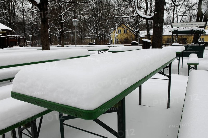 Winter in the English Garden, snow-covered beer garden tables and benches, Munich, Bavaria, Germany