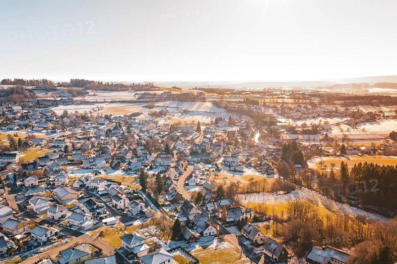 A wintry hilly landscape with a village under snow-covered roofs, surrounded by fields, Hallwangen, Freudenstadt district, Germany