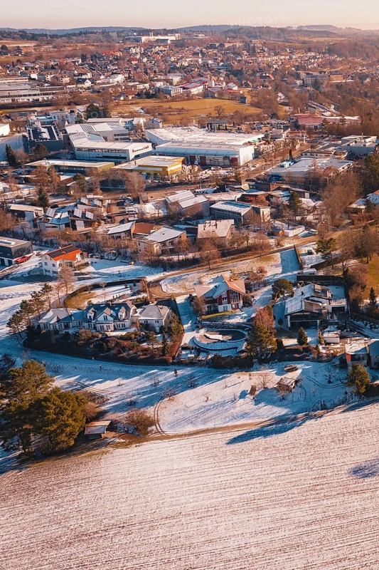 Wintery city view with snow-covered houses and trees in soft orange tones, Hallwangen, Freudenstadt district, Germany