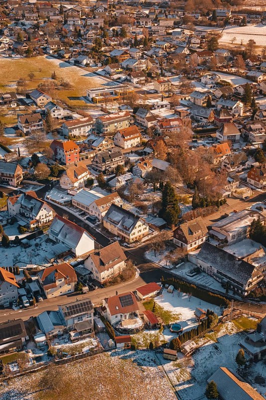 Bird's-eye view of city with snow-covered roofs in winter at sunset, Hallwangen, Freudenstadt district, Germany