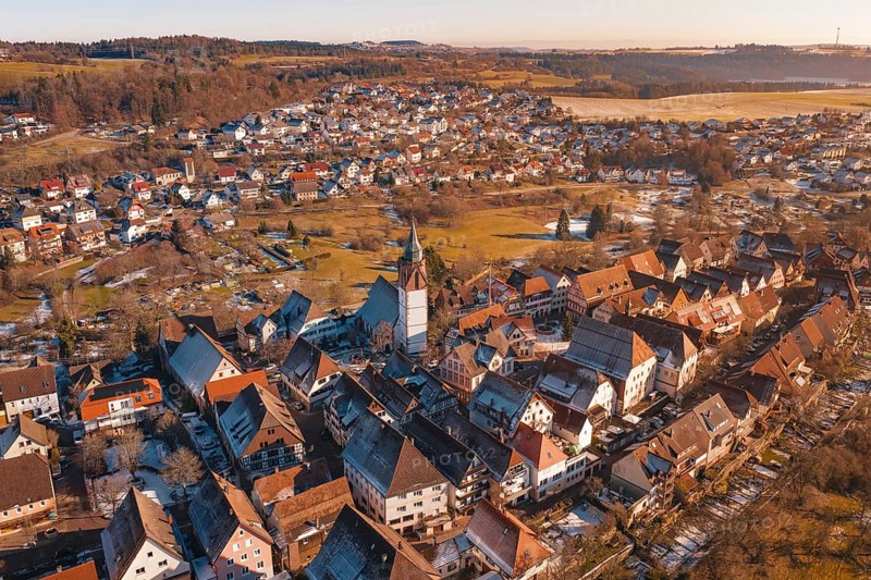 Aerial view of a town with church and buildings in evening light, surrounded by hills and fields, Dornstetten, Freudenstadt district, Germany