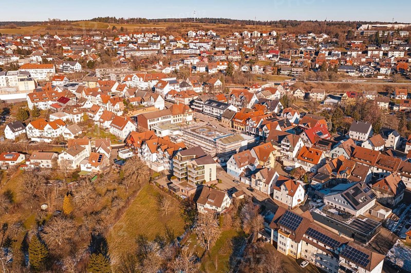 Aerial view of a city with many buildings and red roofs, in a wintry landscape in sunshine, Dornstetten, Freudenstadt district, Germany