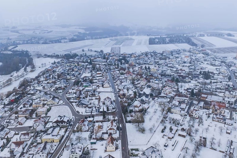 View of a snowy town and surrounding fields surrounded by grey sky, Empfingen, Freudenstadt district, Germany