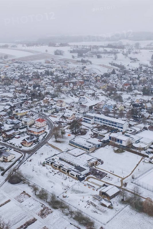 Aerial view of a snowy village with houses, roads and surrounding fields, Empfingen, Freudenstadt district, Germany
