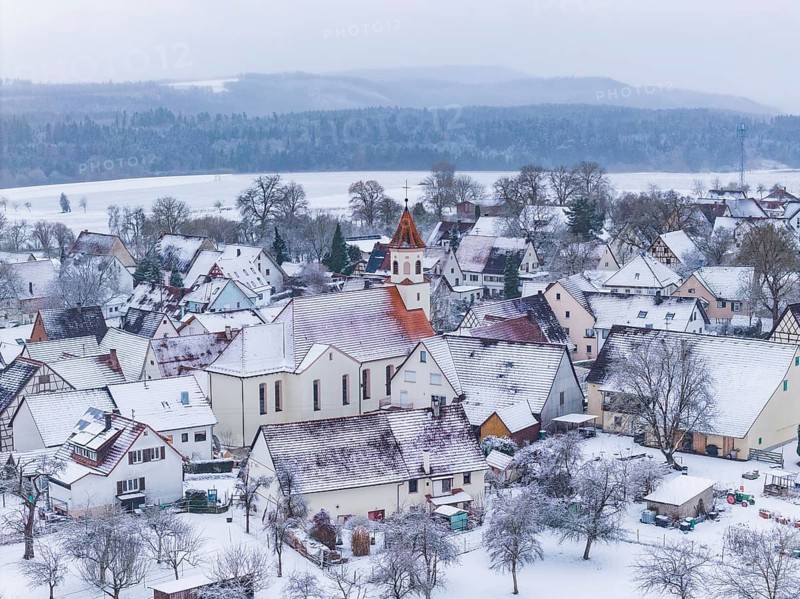 Snowy village landscape in winter, dominating church surrounded by trees, Wiesenstetten, Freudenstadt district, Germany
