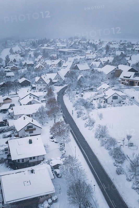 Snowy village with snow-covered houses and roads under cloudy sky, Schopfloch, Freudenstadt district, Germany