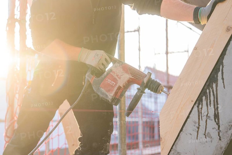 Construction worker drilling wood elements on construction site in sunlight, carpentry construction site, roof extension, renovation, Stuttgart, Germany