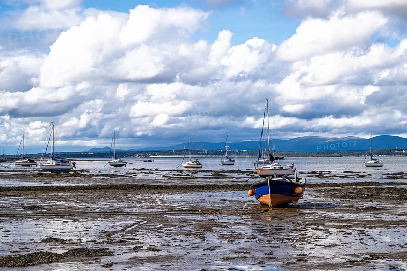 Boats on mud of Forth Estuary over Blackness Castle, Blackness, Scotland, UK