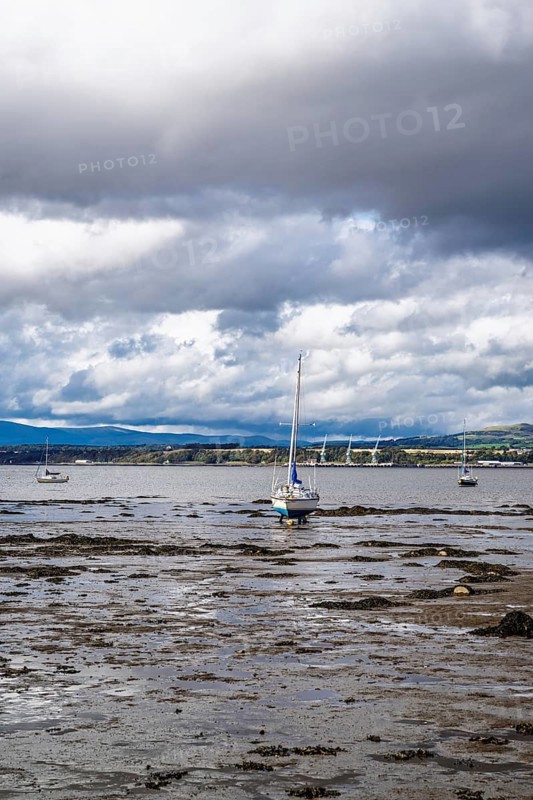 Boats on mud of Forth Estuary over Blackness Castle, Blackness, Scotland, UK
