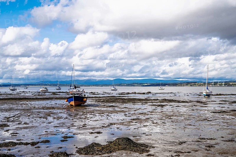 Boats on mud of Forth Estuary over Blackness Castle, Blackness, Scotland, UK