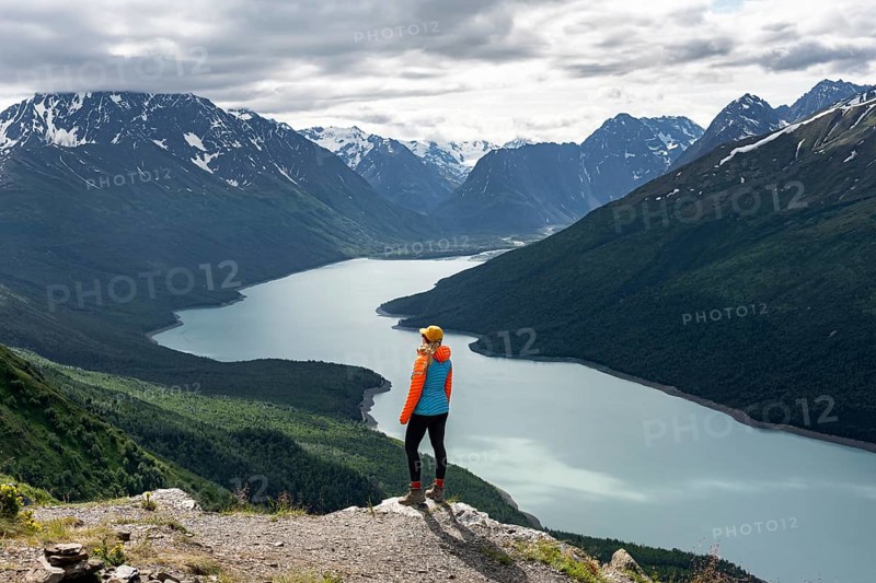 Female mountaineer enjoying views of blue lake and mountains on Twin Peaks Trail, Eklutna Lake, Chugach Mountains, Chugach State Park, Alaska, USA