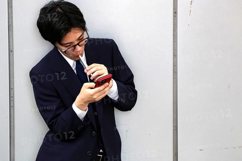 A businessman at Kyoto Central Station, immersed in his smartphone, Kyoto, Japan
