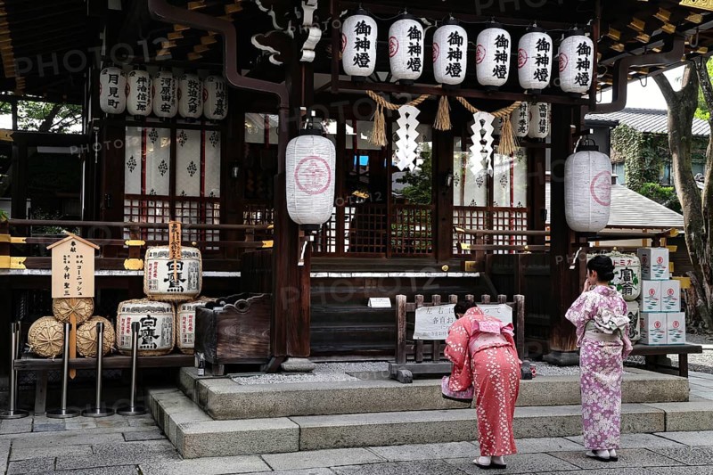 Two woman wearing kimono praying to traditional lanterns at Yasui Konpiragu Temple, Kyoto, Gion, Japan