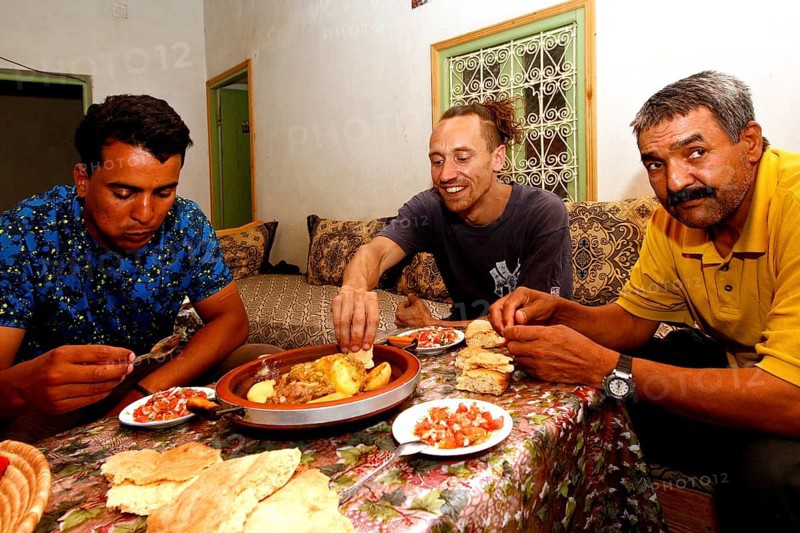 Three men share a traditional Moroccan dinner in a hospitable atmosphere, Errachidia, Morocco