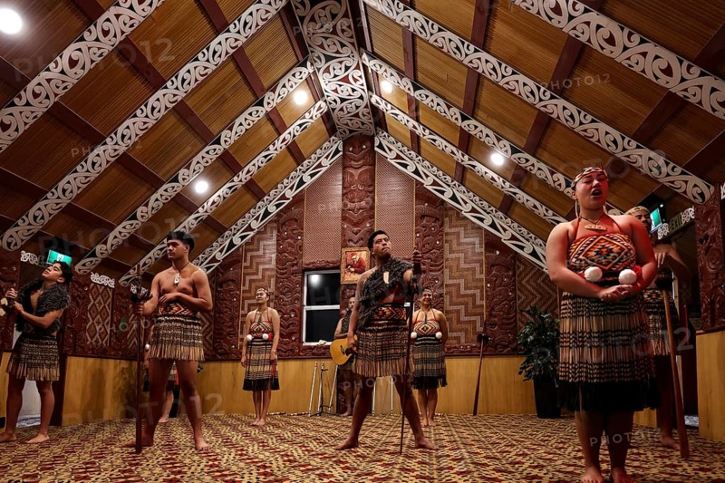 Maori dancers in traditional dress in an ornate meeting house, Rotorua, Te Puia, New Zealand