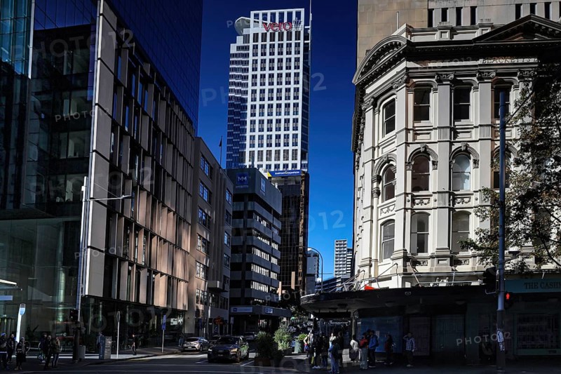 Urban scene along Queen Street with modern buildings against blue sky, Auckland, New Zealand