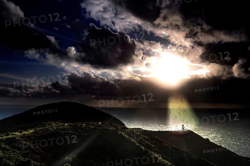 Sunset over the ocean at Cape Reinga with rolling clouds and rays of light, Cape Reinga, Northland, New Zealand