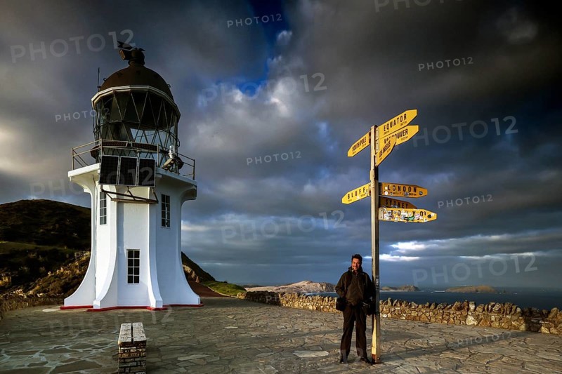 Lighthouse and yellow signpost at Cape Reinga under dramatic sky, Cape Reinga, Northland, New Zealand