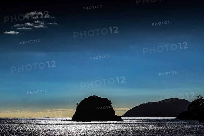 A silhouette of an island against a dark blue sky at sunset, Bay of Islands, New Zealand