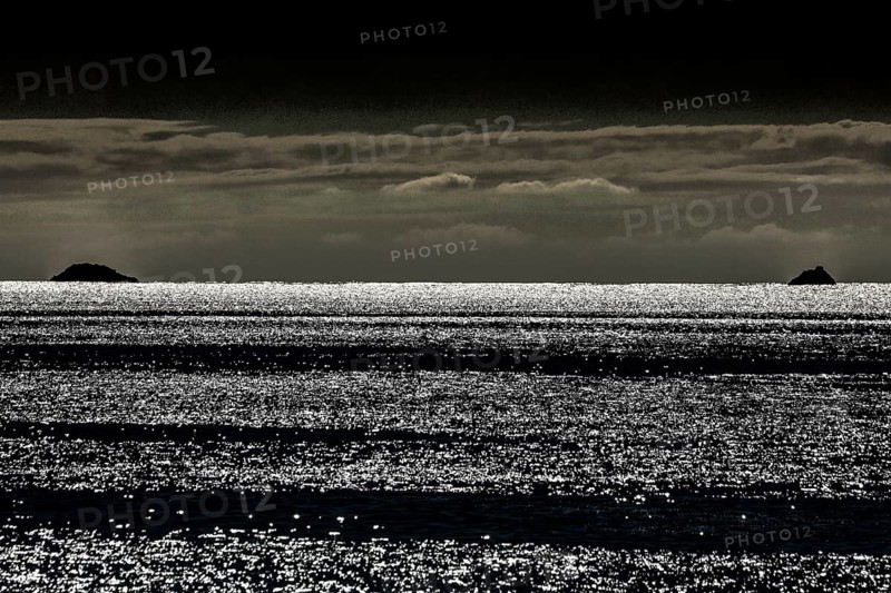 Waves reflect light and create an atmospheric image at dusk, Bay of Islands, New Zealand