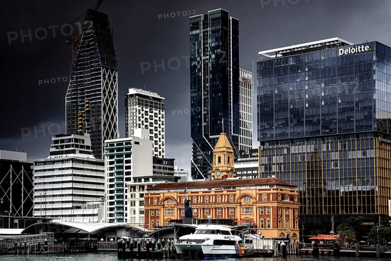 Auckland Ferry Building against a modern skyline and cloudy sky, Auckland, zero, New Zealand
